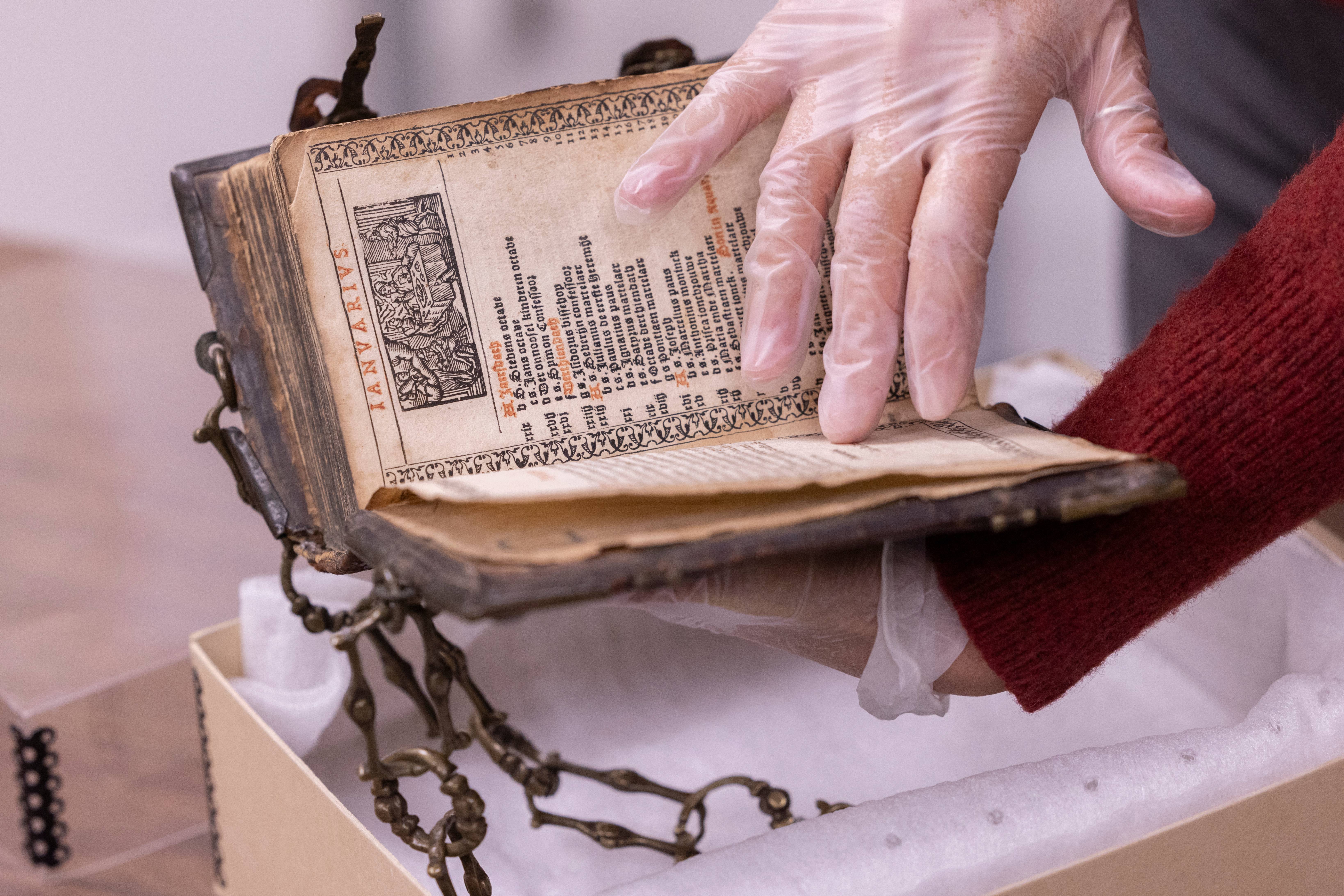 Gloved hands handling an old, perserved book